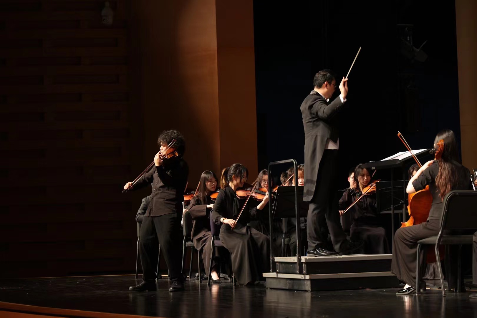 A soloist, conductor and orchestra sharing the stage.